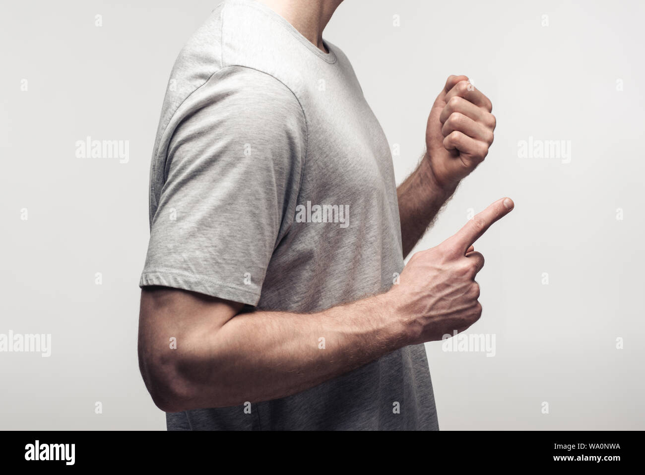 Vista parziale dell'uomo il pugno di contenimento e puntando con il dito isolati su grigio, emozioni umane e concetto di espressione Foto Stock