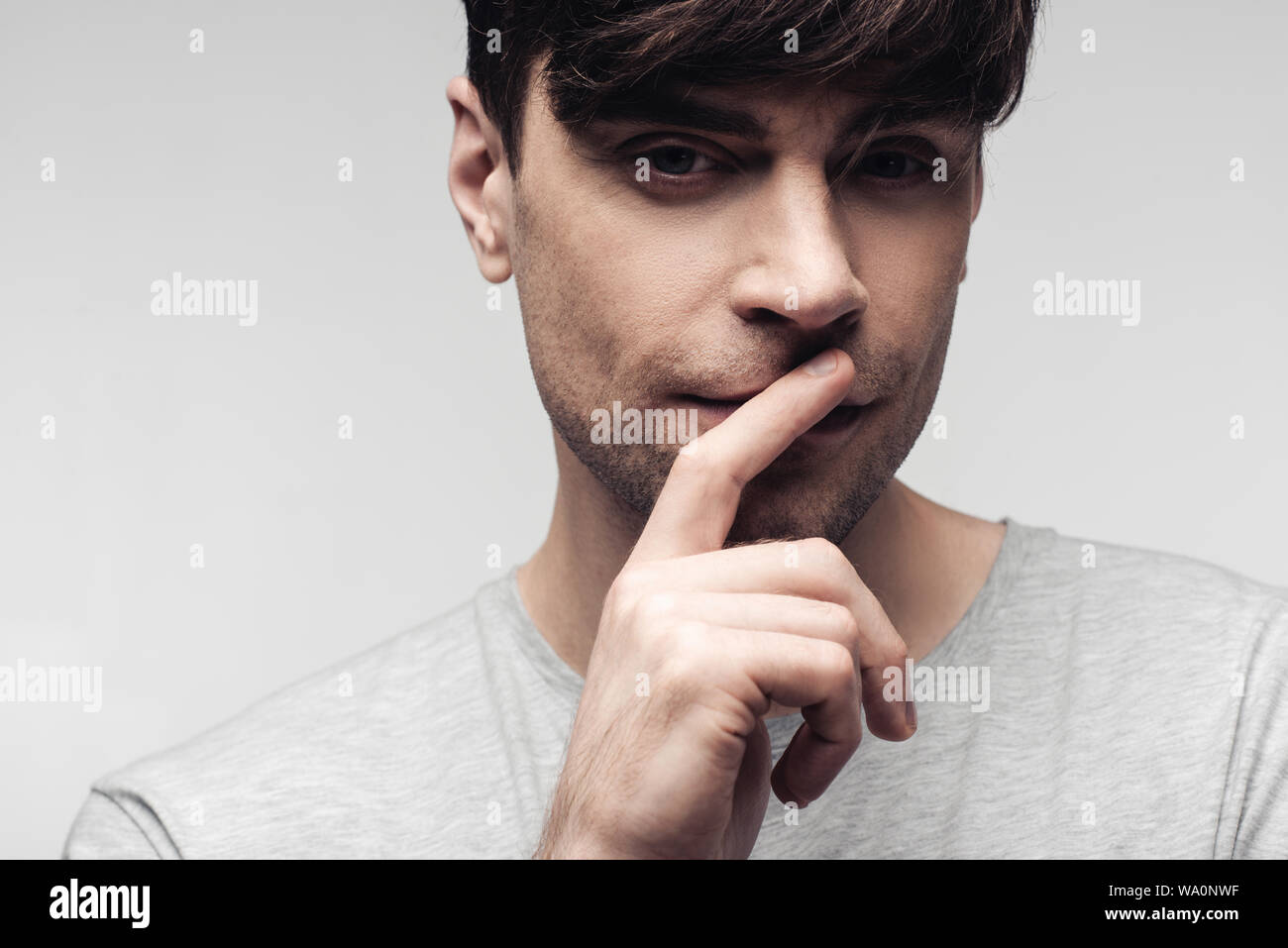 Malinconici muto che mostra il silenzio gesto isolato sul grigio, emozioni umane e concetto di espressione Foto Stock