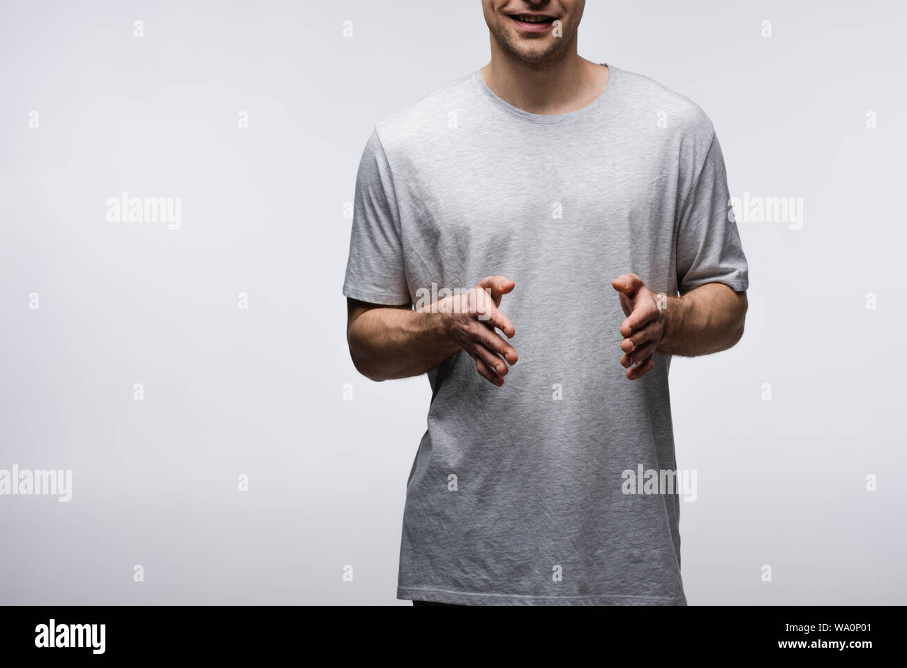Vista ritagliata dell uomo sorridente che mostra dimensioni gesto isolato sul grigio, emozioni umane e concetto di espressione Foto Stock