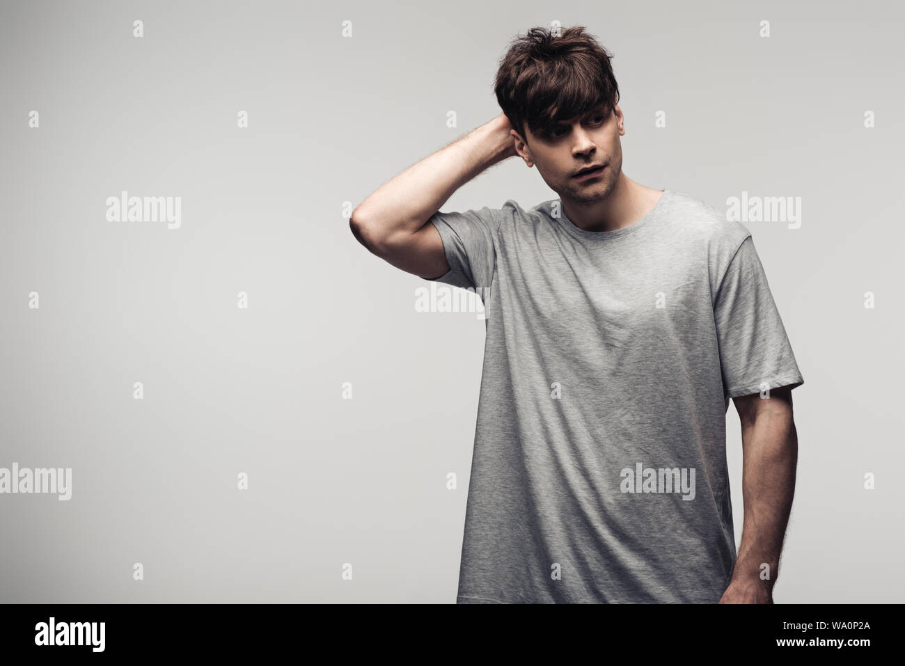 Malinconici man mano tenuta vicino al viso e guardando lontano isolati su grigio, emozioni umane e concetto di espressione Foto Stock