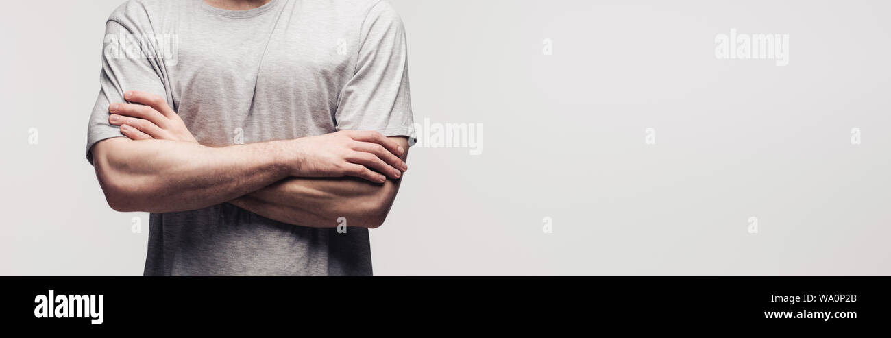 Vista ritagliata dell uomo in piedi con le braccia conserte isolati su grigio, scatto panoramico, emozione umana e il concetto di espressione Foto Stock