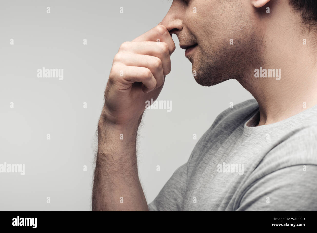 Vista parziale di pensieroso uomo tocca naso isolati su grigio, emozioni umane e concetto di espressione Foto Stock