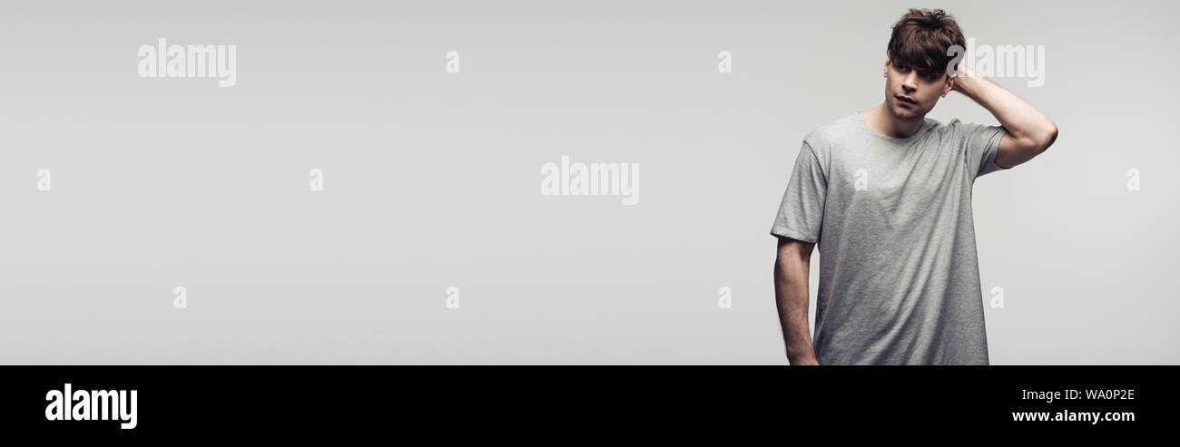Panoramica di pensosa azienda man mano dietro la testa isolata sul grigio, emozioni umane e concetto di espressione Foto Stock