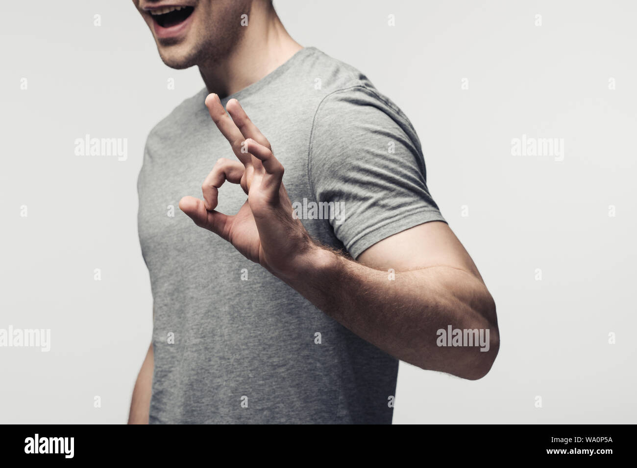 Vista ritagliata della giovane uomo che mostra ok gesto isolato sul grigio, emozioni umane e concetto di espressione Foto Stock