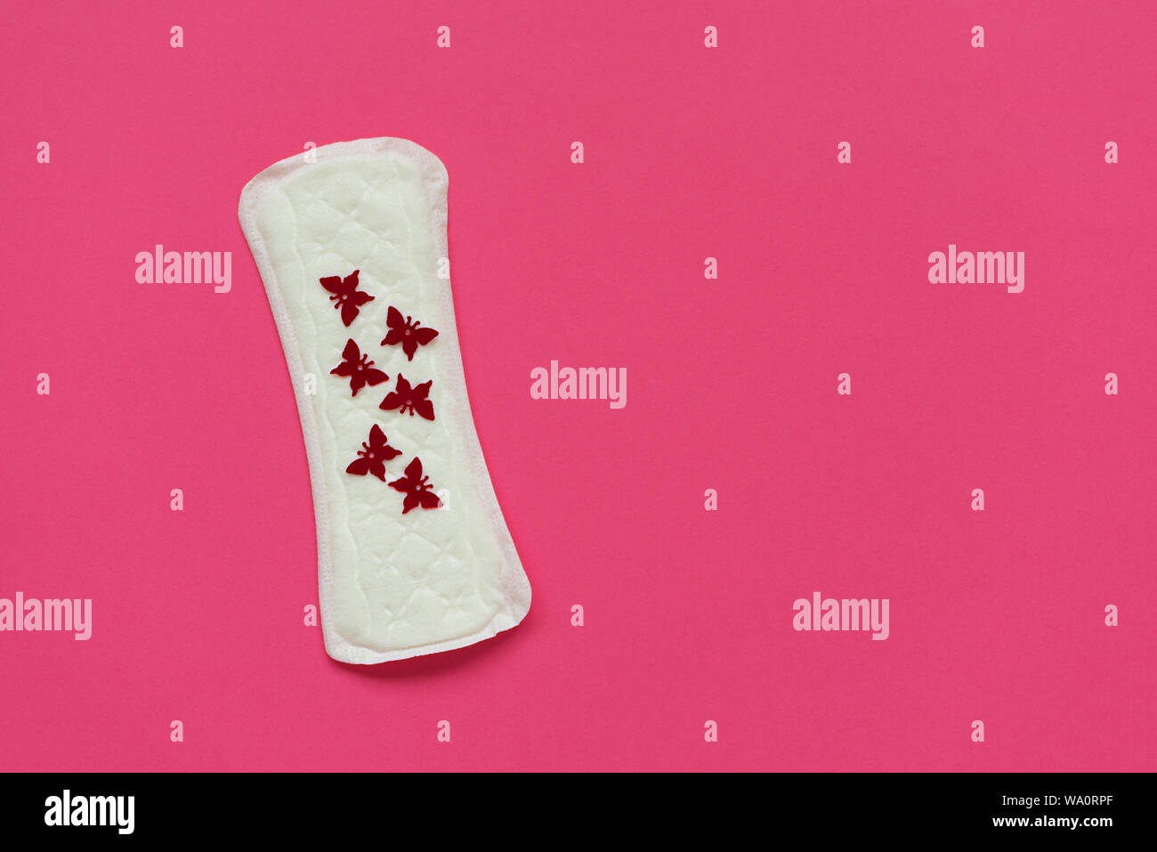 Assorbenti igienici o pad con red butterfly luccica su sfondo rosa. Femmina igiene intima concetto. Vista dall'alto. Copia dello spazio. Foto Stock