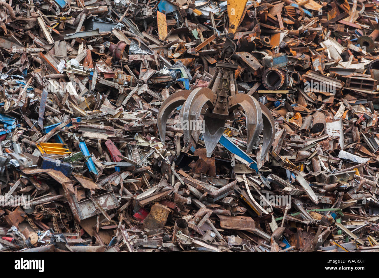 Artiglio metallico la caduta dei rifiuti industriali di metallo su un enorme mucchio. Foto Stock