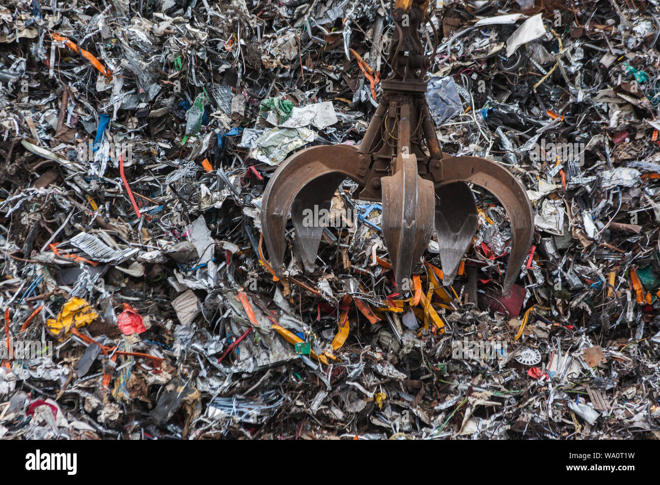 Artiglio metallico la caduta dei rifiuti industriali di metallo su un enorme mucchio. Foto Stock