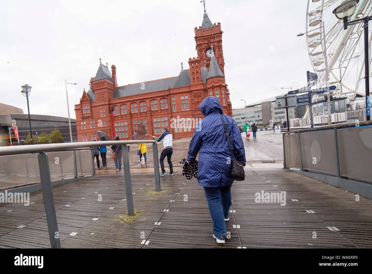 Cardiff Wales, Regno Unito, 16 agosto 2019. Persone battaglia gli elementi nella Baia di Cardiff come un mese di pioggia cade attraverso gran parte del Galles e Inghilterra, con giallo avvisi meteo in luogo. Foto Stock