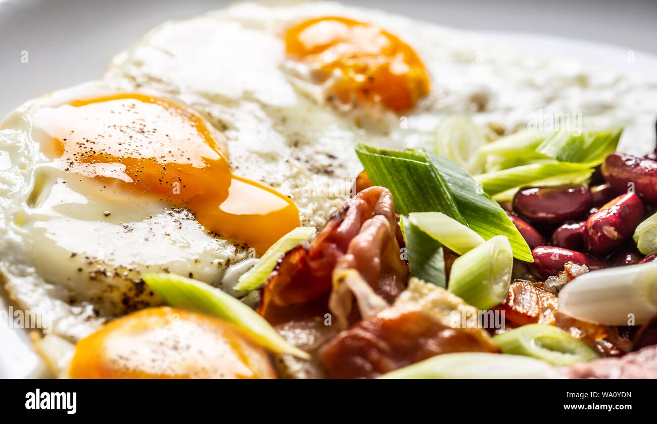 Prima colazione Inglese con uova, pancetta, fagioli e cipolle iyoung nella piastra bianca Foto Stock