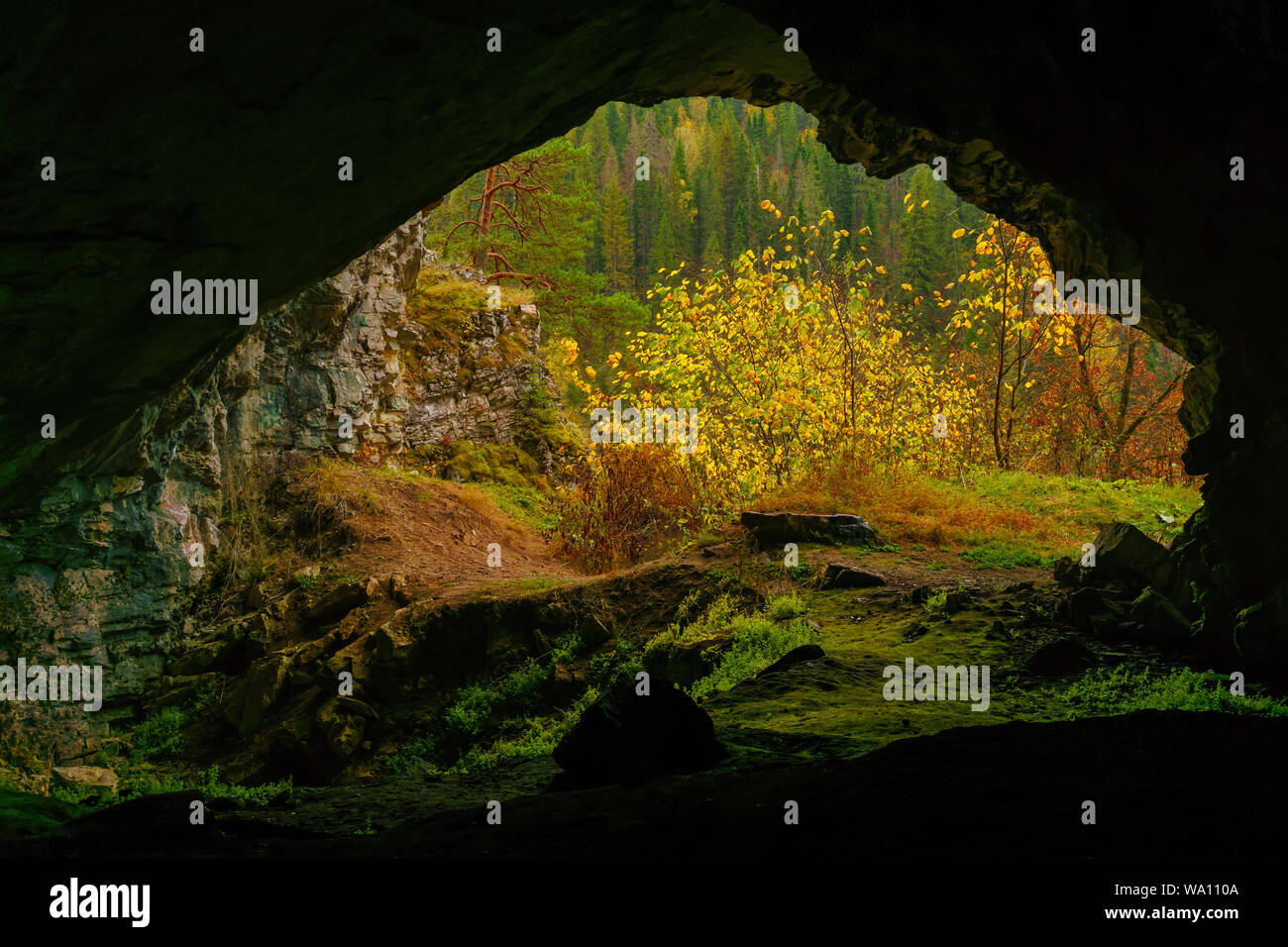 Vista dal buio grotta naturale per l'autunno luminoso paesaggio di montagna al di fuori Foto Stock