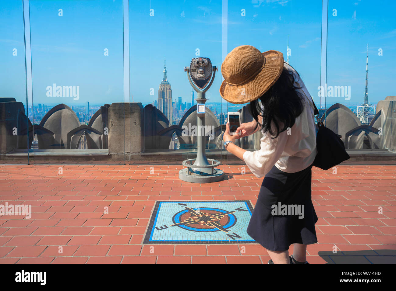 Fotografia di viaggio, vista posteriore di una giovane donna di scattare una foto del Rockefeller Center Observation Deck in Midtown Manhattan, a New York City, Stati Uniti d'America Foto Stock