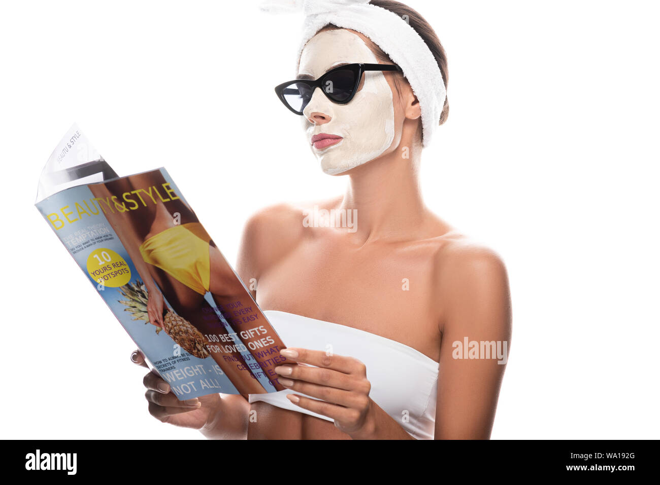 Donna in cosmetici fascia per capelli e occhiali da sole con maschera viso  rivista lettura isolato su bianco Foto stock - Alamy