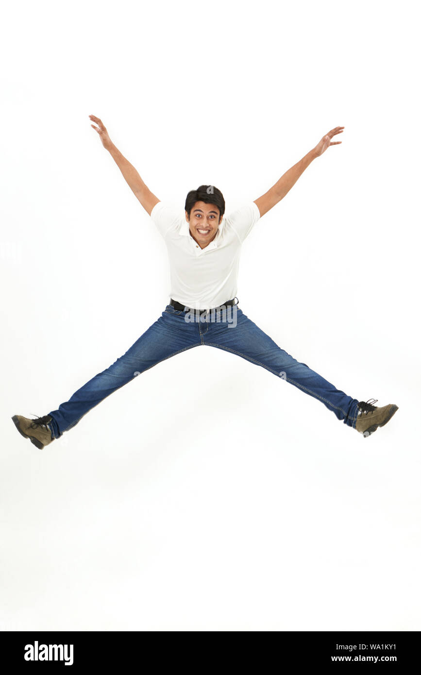 Giovane uomo salti in aria e sorridente Foto Stock