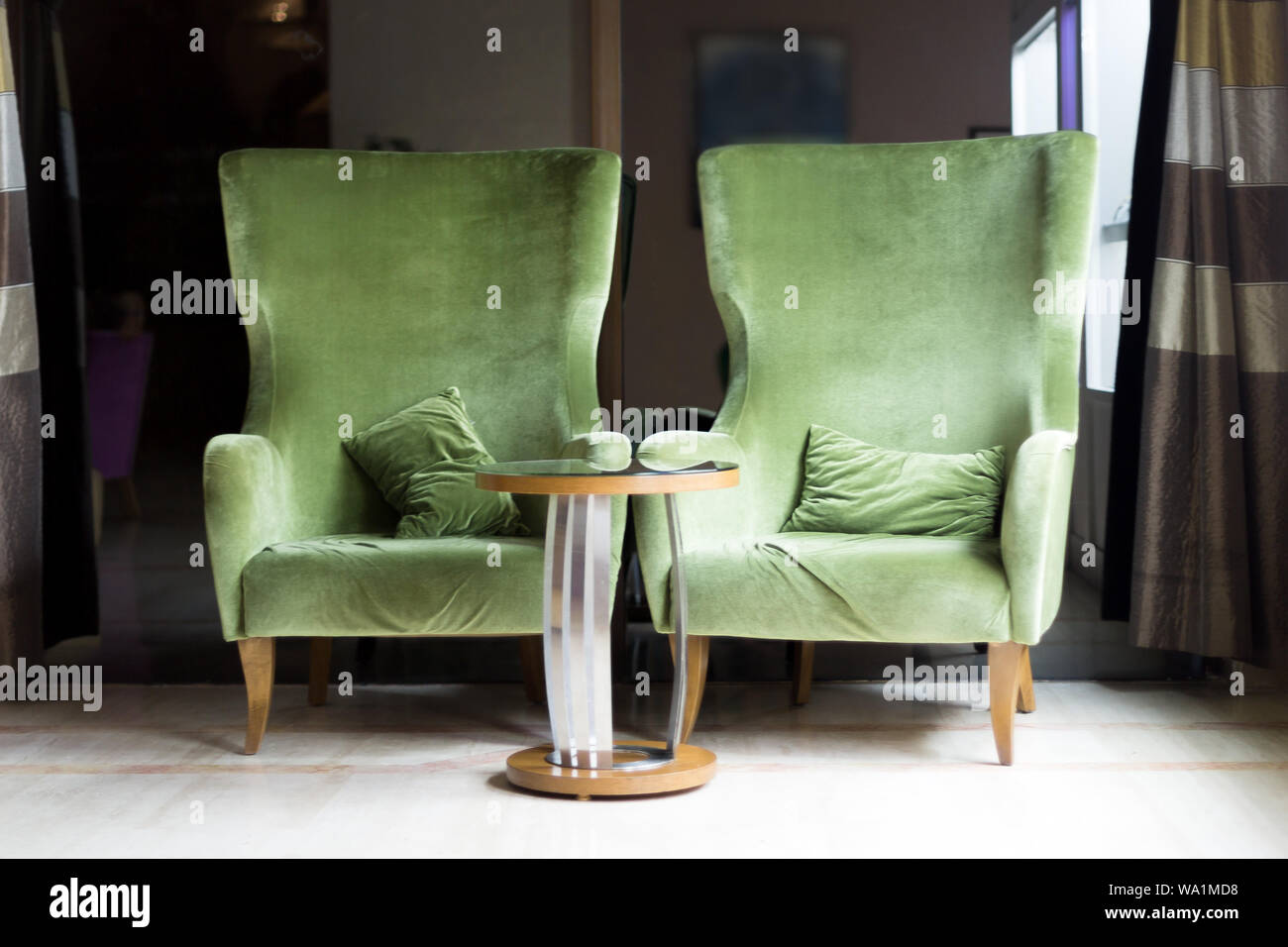 Due sedie di velluto verde e un tavolo da caffè Foto Stock