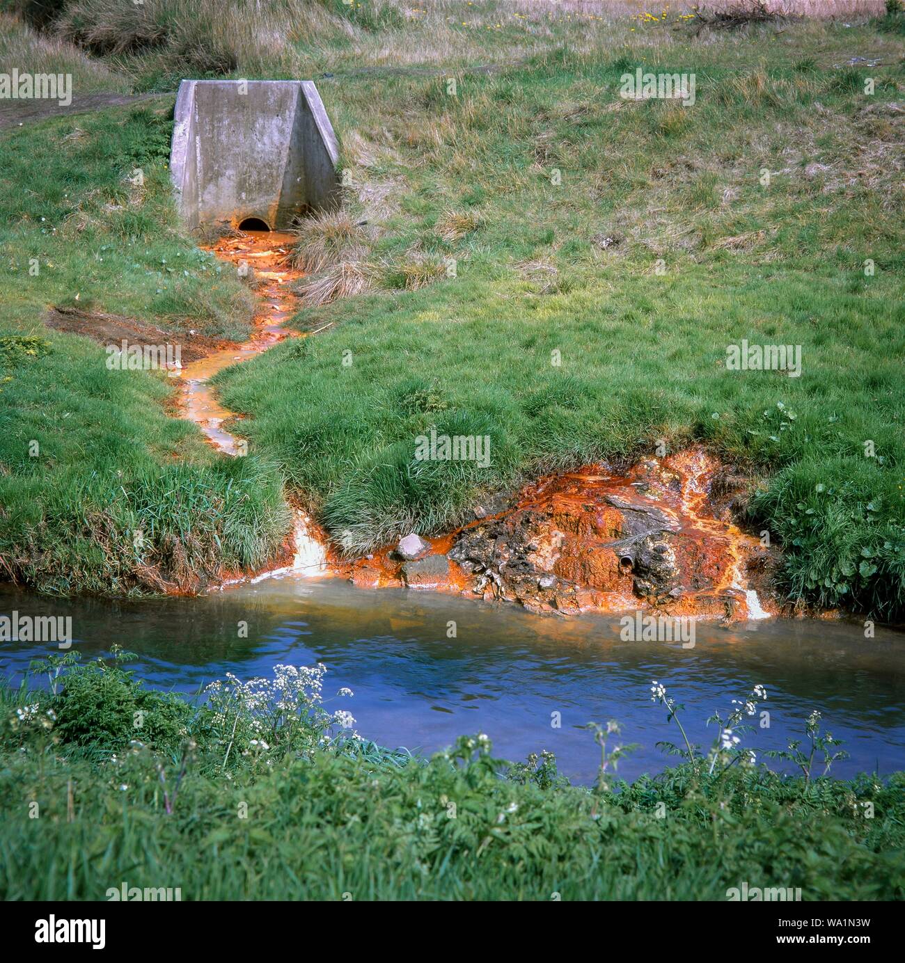 Chimicamente l acqua inquinata da scaricare nel fiume domare al di fuori della terra una volta utilizzati per scaricare i rifiuti contenenti metalli pesanti. West Midlands, Regno Unito. Foto Stock