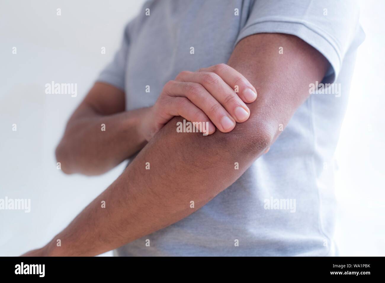 Uomo di toccare il suo gomito nel dolore. Foto Stock