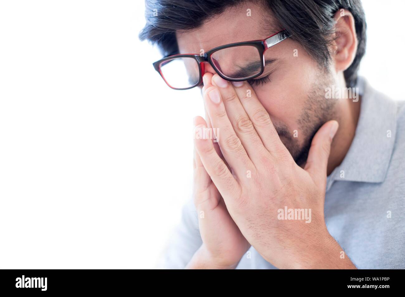 Uomo di pizzicare il ponte del suo naso, indossando occhiali. Foto Stock