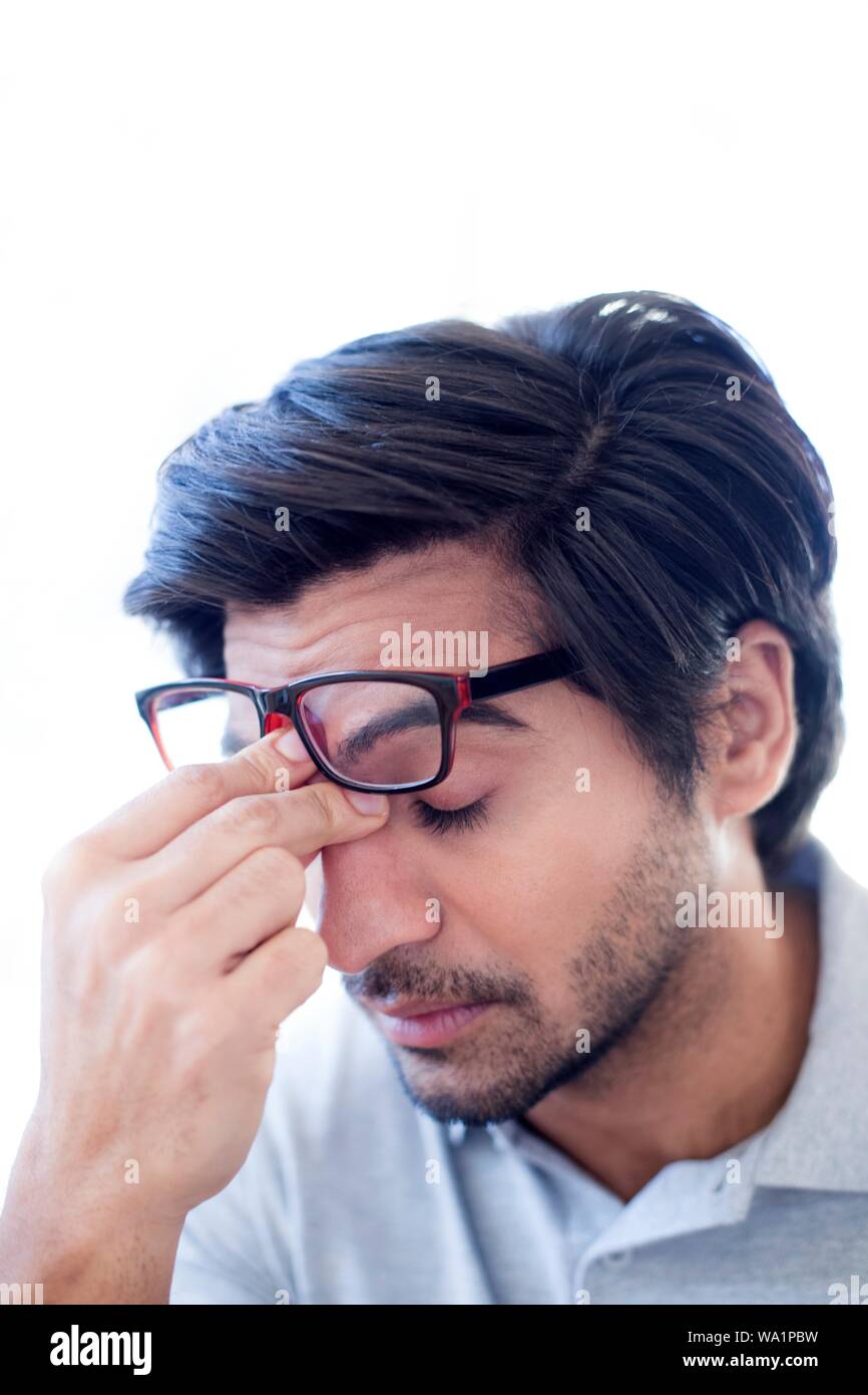 Uomo di pizzicare il ponte del suo naso, indossando occhiali. Foto Stock