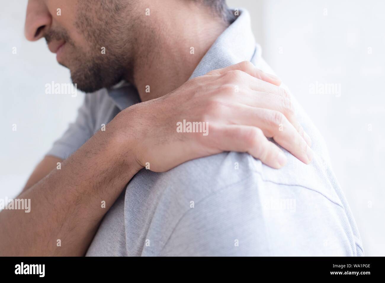 Uomo di toccare la sua spalla nel dolore. Foto Stock