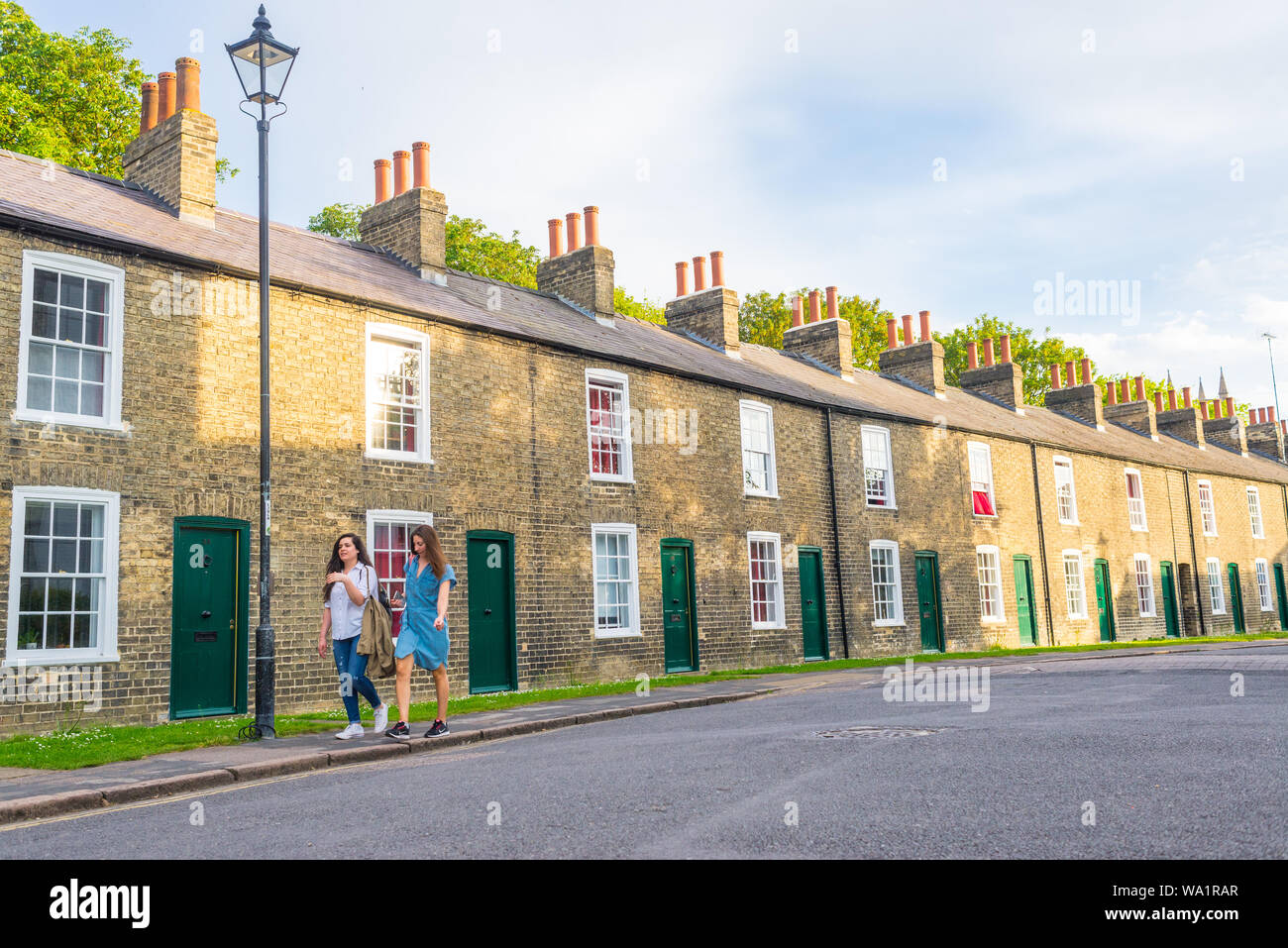 Cambridge, Regno Unito - Giugno 2019: giovani donne matura a piedi nella parte anteriore del tenements tradizionali case in stile vittoriano a Cambridge nel Regno Unito. Foto Stock