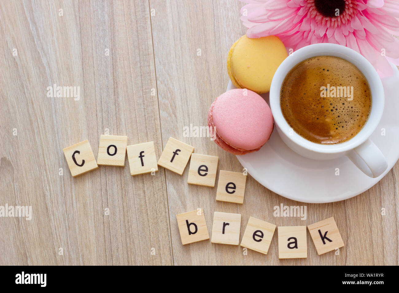Buon pomeriggio messaggio pausa caffè concetto tazza bianca di spuma di caffè espresso con colorate amaretti francese su sfondo di legno, lo spazio per il testo. Foto Stock