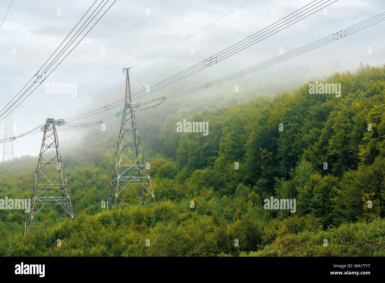 Le linee elettriche in alta tensione nella torre montagne. L'erogazione di energia background. efficiente di erogazione di elettricità concetto. tempo nebbioso con cielo nuvoloso Foto Stock