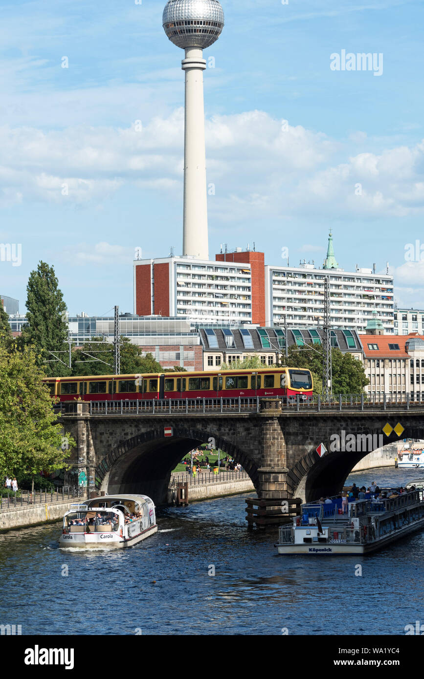 Tour barche sul Fiume Spree passando sotto il ponte Stadtbahn dall isola dei musei con la torre della TV in distanza, Berlino, Germania. Foto Stock