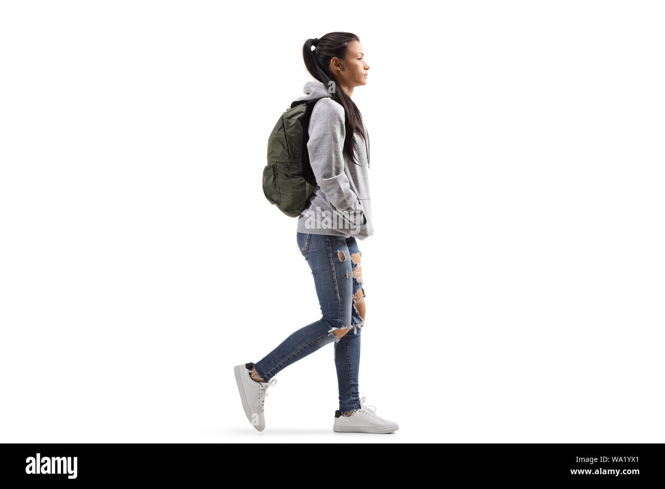 Lunghezza piena ripresa di profilo di una studentessa di indossare una felpa con cappuccio e jeans strappati pochi isolati su sfondo bianco Foto Stock
