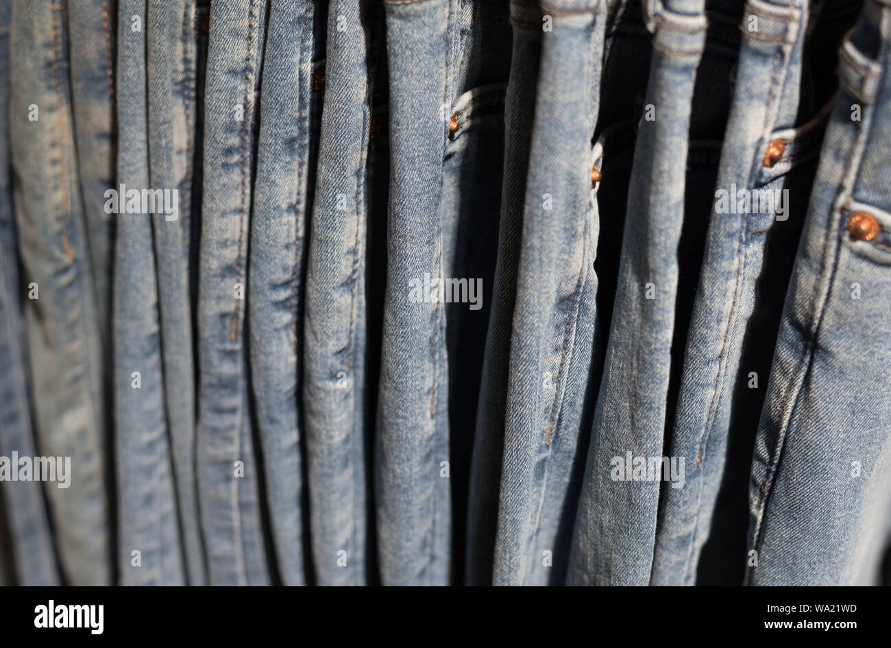 Jeans appesi a un negozio rack, una vista laterale e una vista dettagliata. Tessuto denim, sfondo sfocato (profondità di campo). Foto Stock