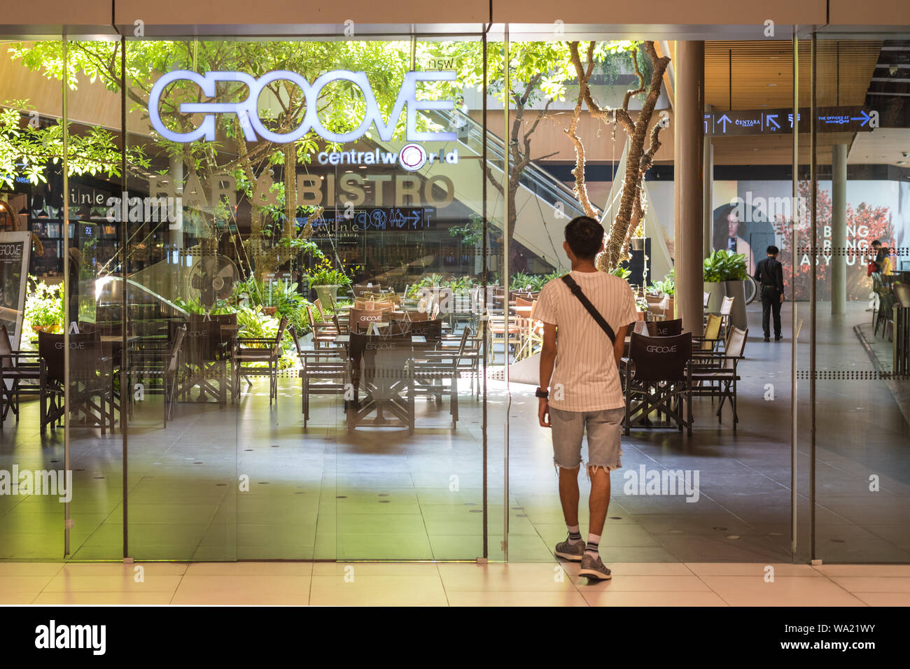 Bangkok, Tailandia - 19 Maggio 2019: un uomo cammina nella scanalatura ristorante verso l'interno decorato con alberi viventi al Central World shopping mall. Foto Stock