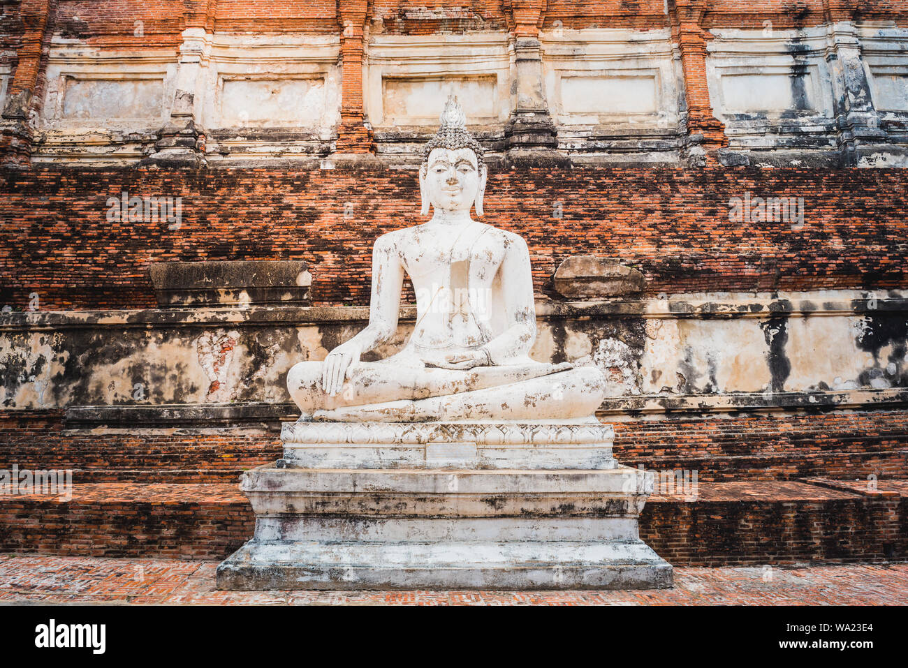 Statua del Buddha sul vecchio muro sfondo in una città antica in Thailandia. Medievale tempio Buddista Wat Yai Chai Mongkhon (Wat Yai Chaimongkol). Foto Stock