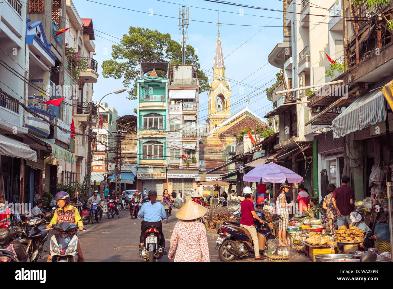 La città di Ho Chi Minh, Vietnam - 1 Maggio 2019: una pittoresca strada di Cholon occupata dalle attività di mercato, con una vista di case a schiera e Cha Tam Chiesa. Foto Stock