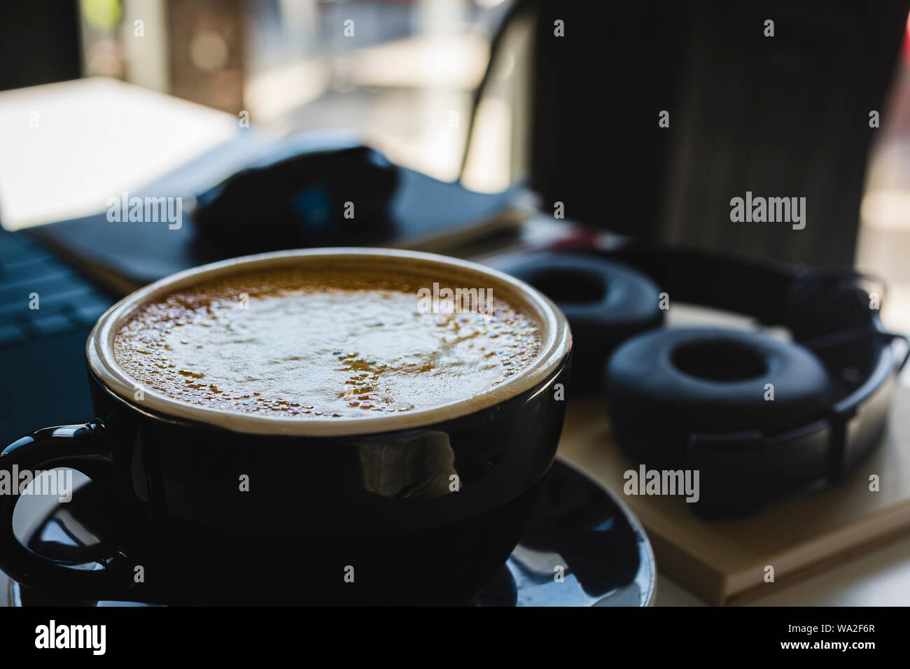 Studiare con un delizioso cappuccino circondato da materiali di studio e di elettronica. Foto Stock