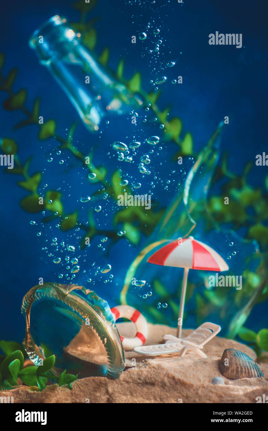 Ombrellone e sedia a sdraio subacquei con bolle e alghe. Annegamento di città e il riscaldamento globale del concetto. Concettuale vita ancora con miniature. Foto Stock