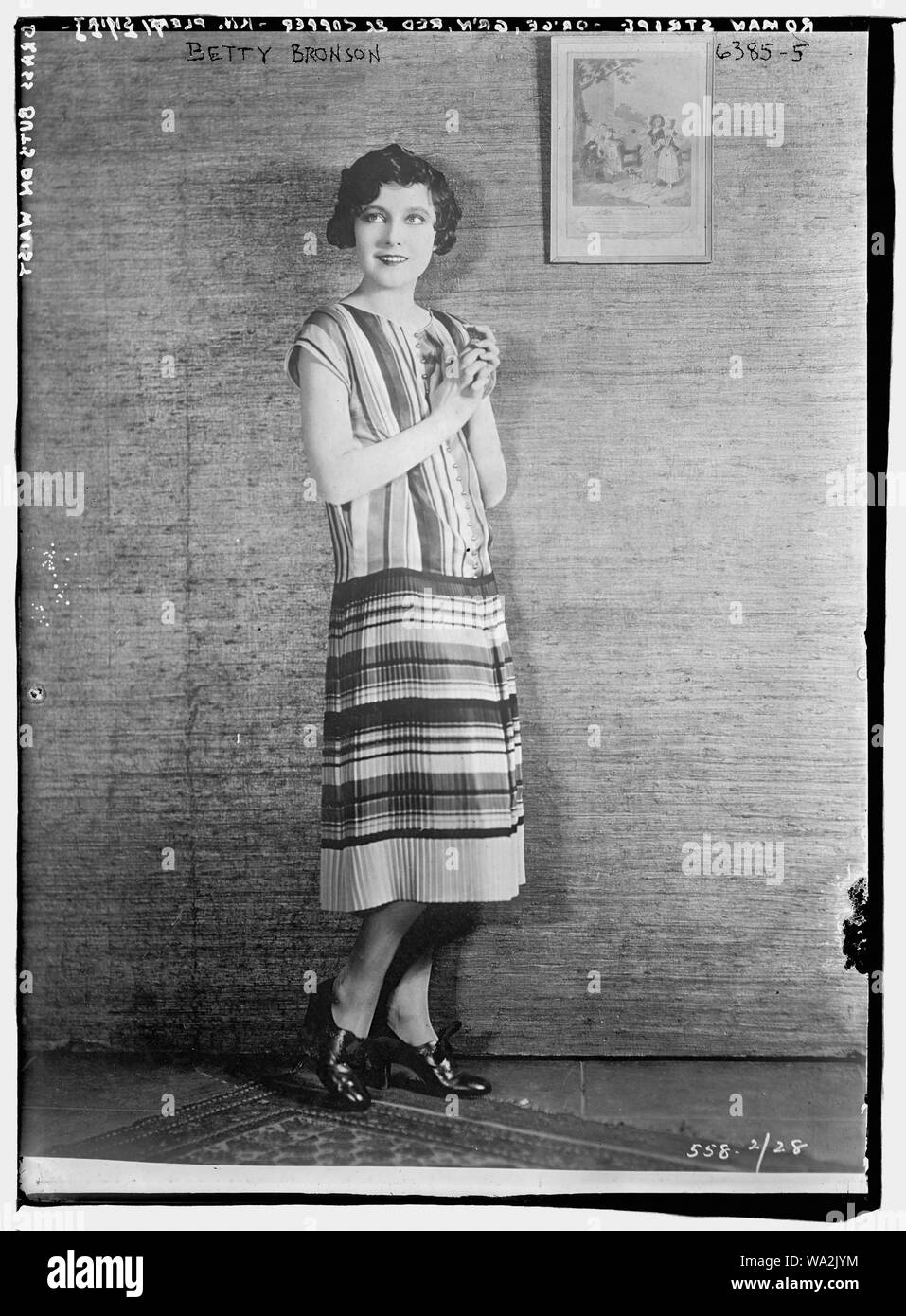 Betty Bronson modellazione Stripe Romana -- arancione, verde, rosso e rame lavorato a maglia gonna plissettata con pulsanti in ottone Foto Stock