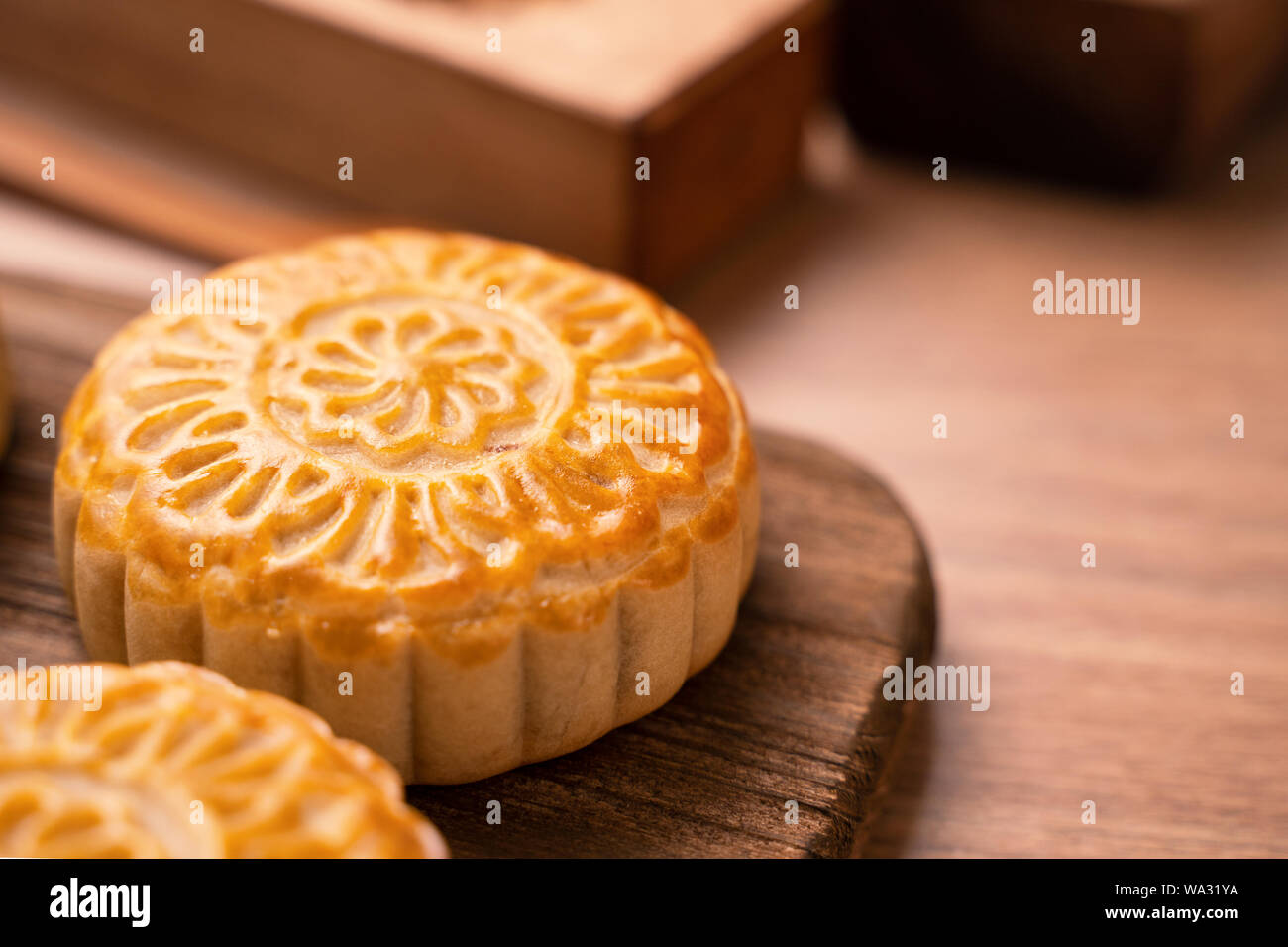 Una forma rotonda sfornato fresco torta della luna - pasticceria Cinese per moonckae Mid-Autumn Festival di luna su sfondo di legno e serve il vassoio, close up, spazio di copia Foto Stock