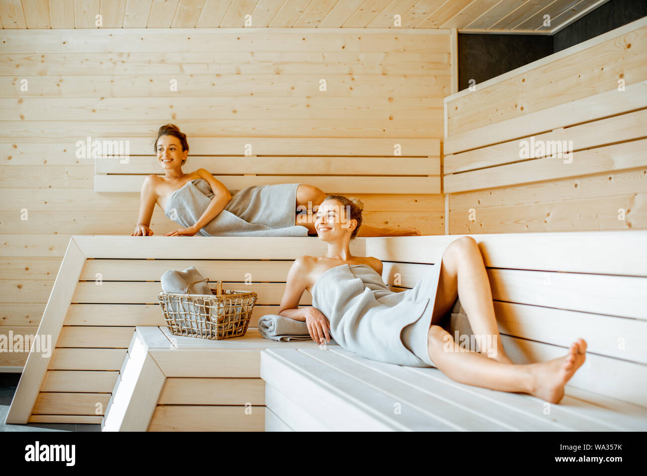 Due giovani fidanzate coperto con lastre rilassarsi nella sauna di lusso. Concetto di amicizia femminile e il trattamento termale Foto Stock