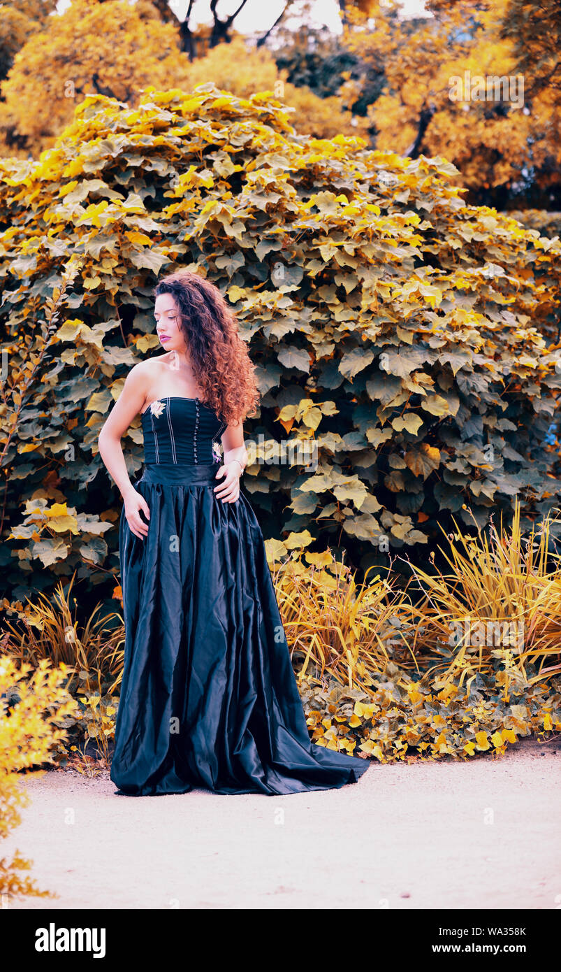 Giovane e bella donna che indossa Lungo abito nero in natura Foto Stock