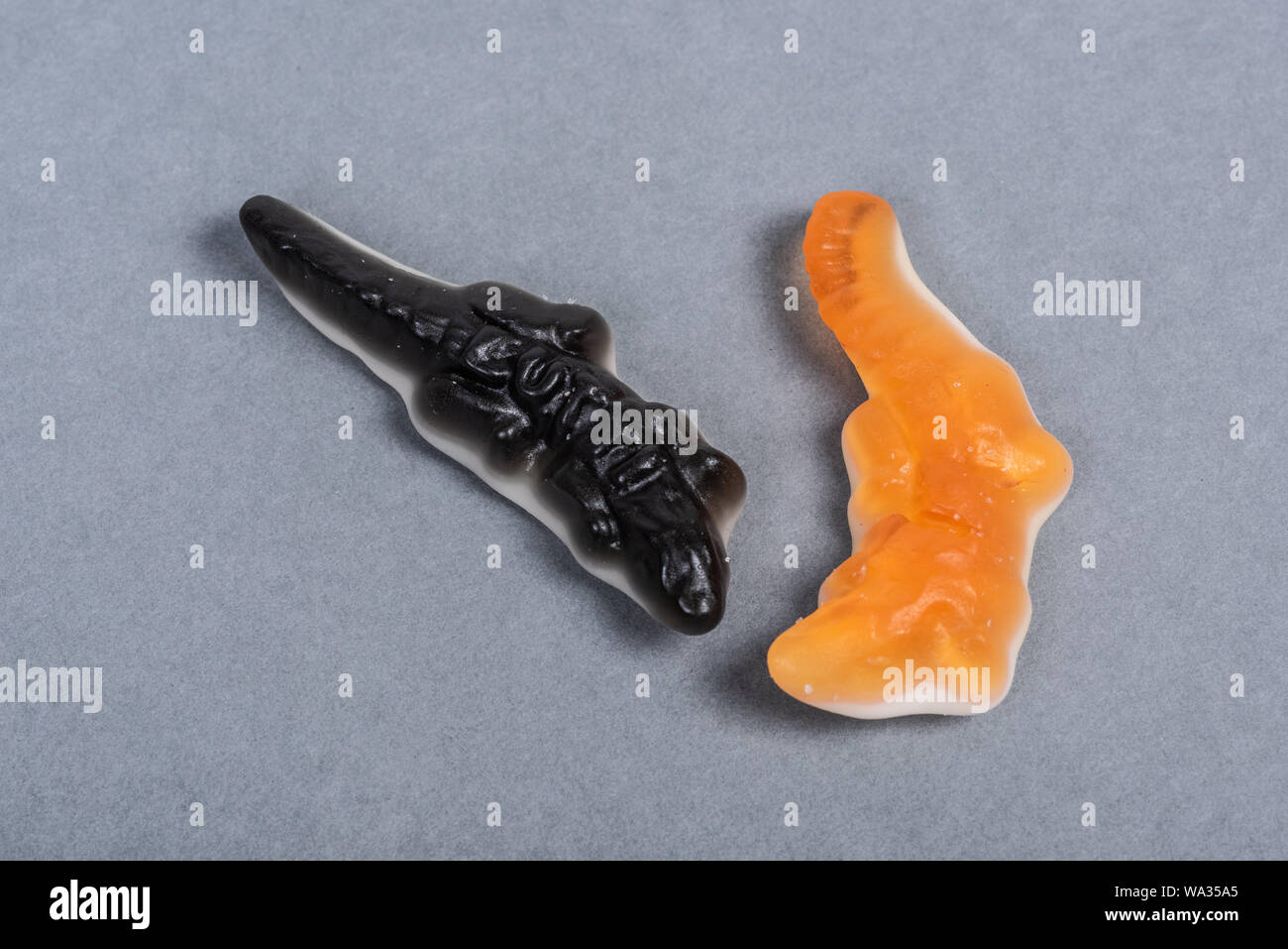 Nero e arancio vino coccodrilli di gomma su sfondo grigio. Foto Stock