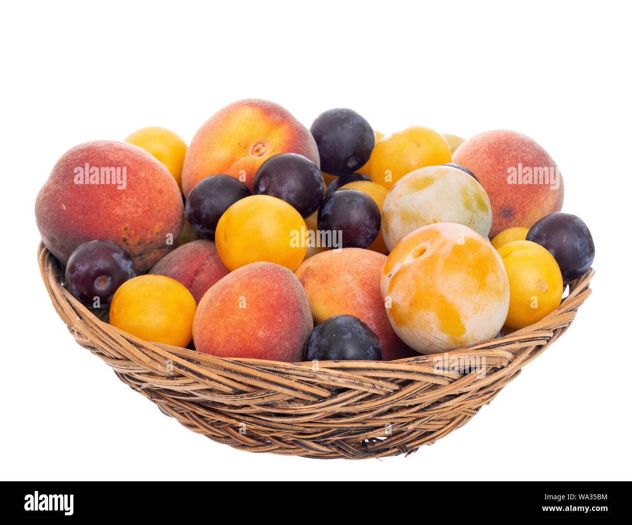 In vecchio stile frutti da un lungo abbandonato orchard nel vecchio cesto di vimini, ciotola. Tiny prugne, dolce e piccola pesche ecc. Vista frontale. Isolato. Foto Stock