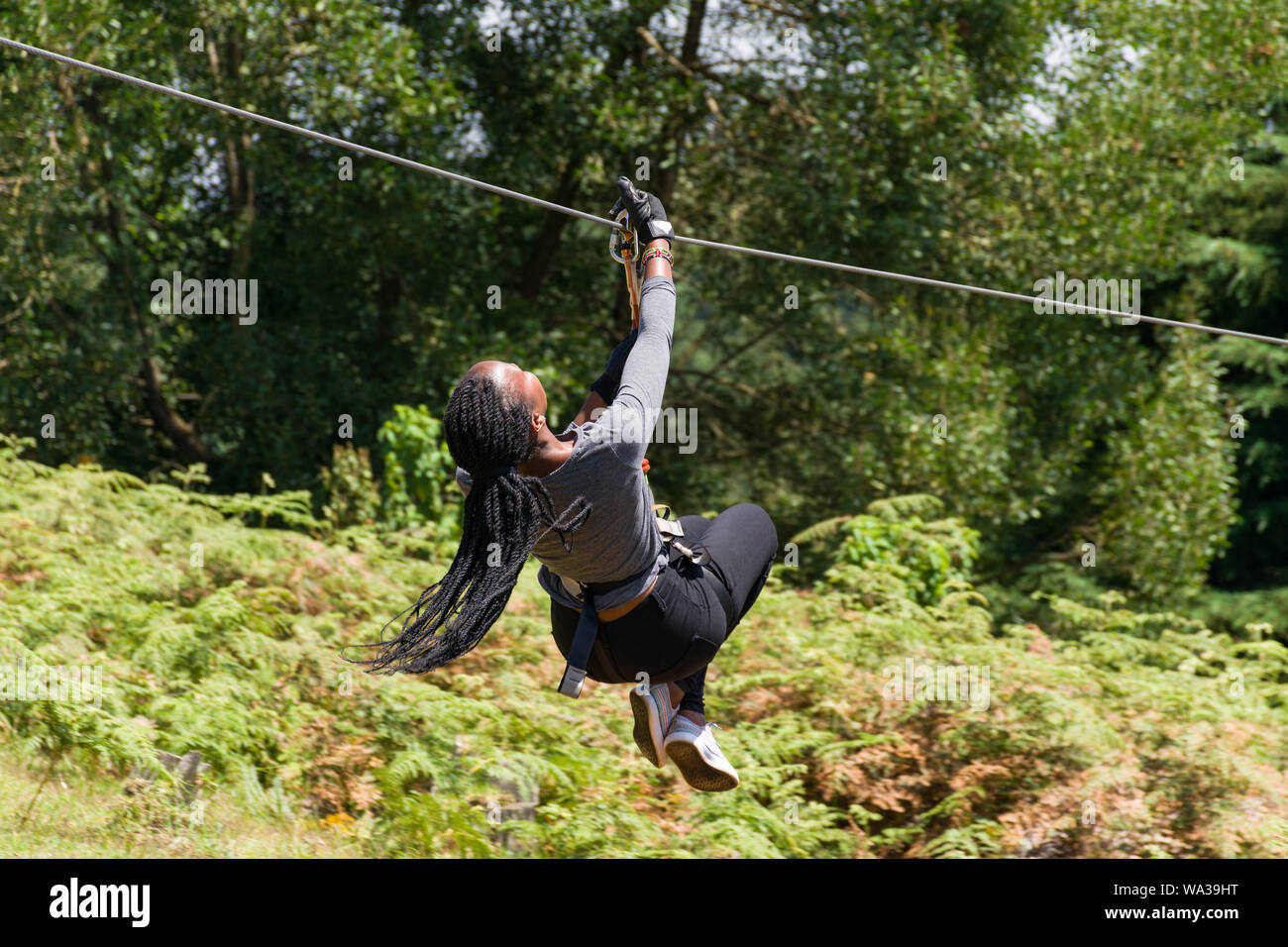 Una giovane donna keniota che viaggiano su una linea di cerniera in corrispondenza della foresta il centro ricreativo, Kenya Foto Stock