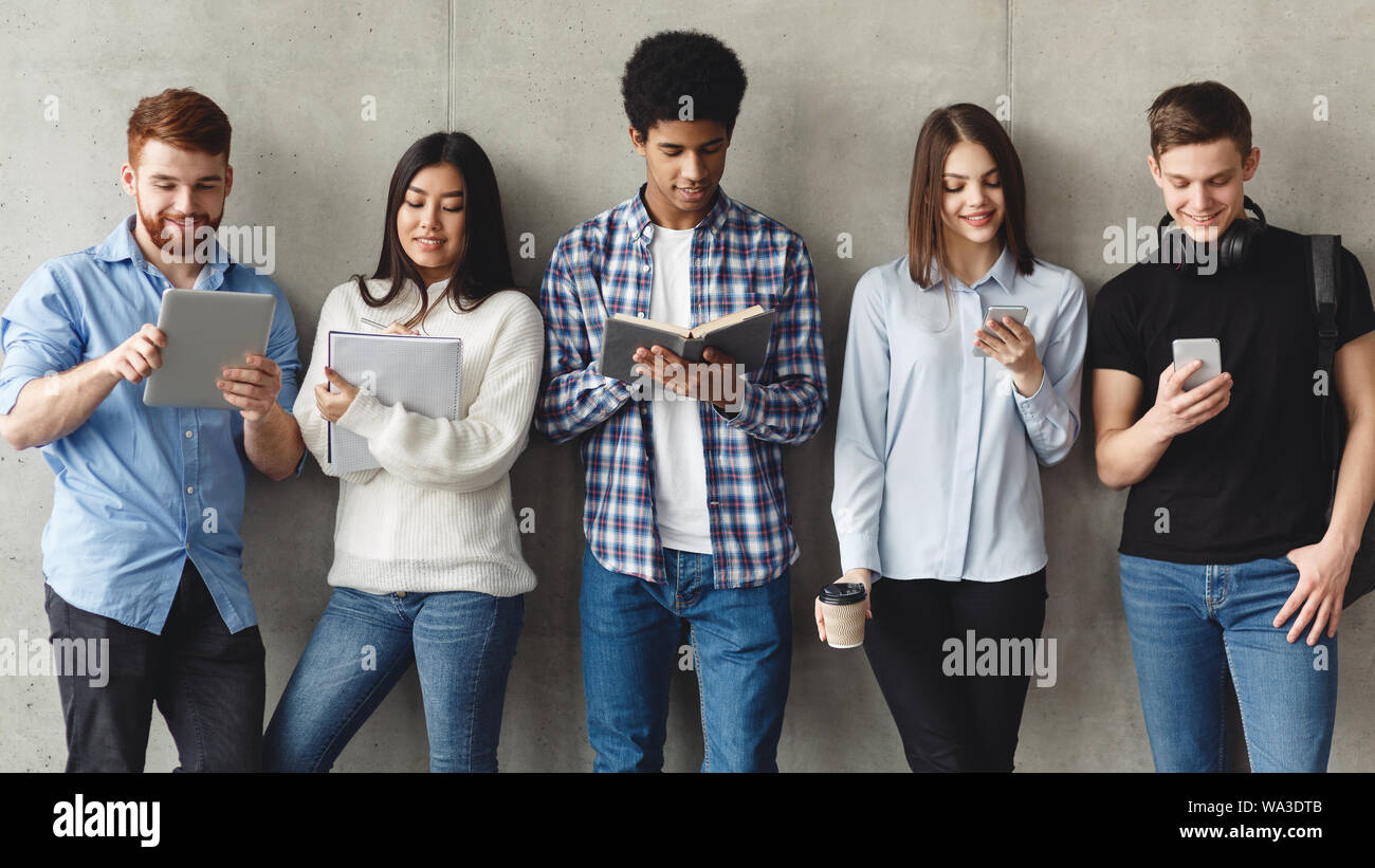 Diversi studenti con libri in piedi vicino al muro grigio Foto Stock