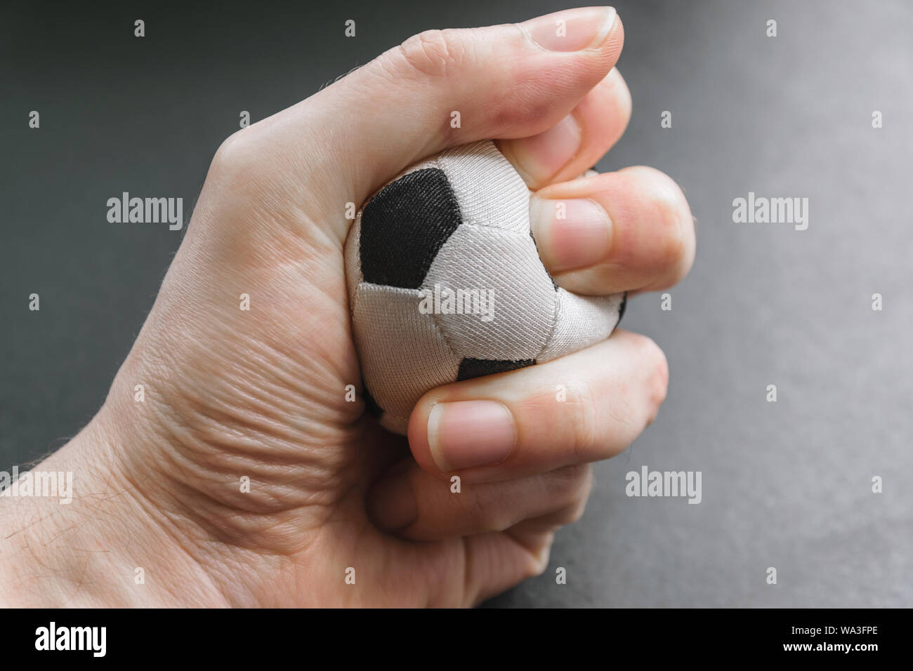 Stringe la mano una piccola palla calcio - foto concettuale. Foto Stock