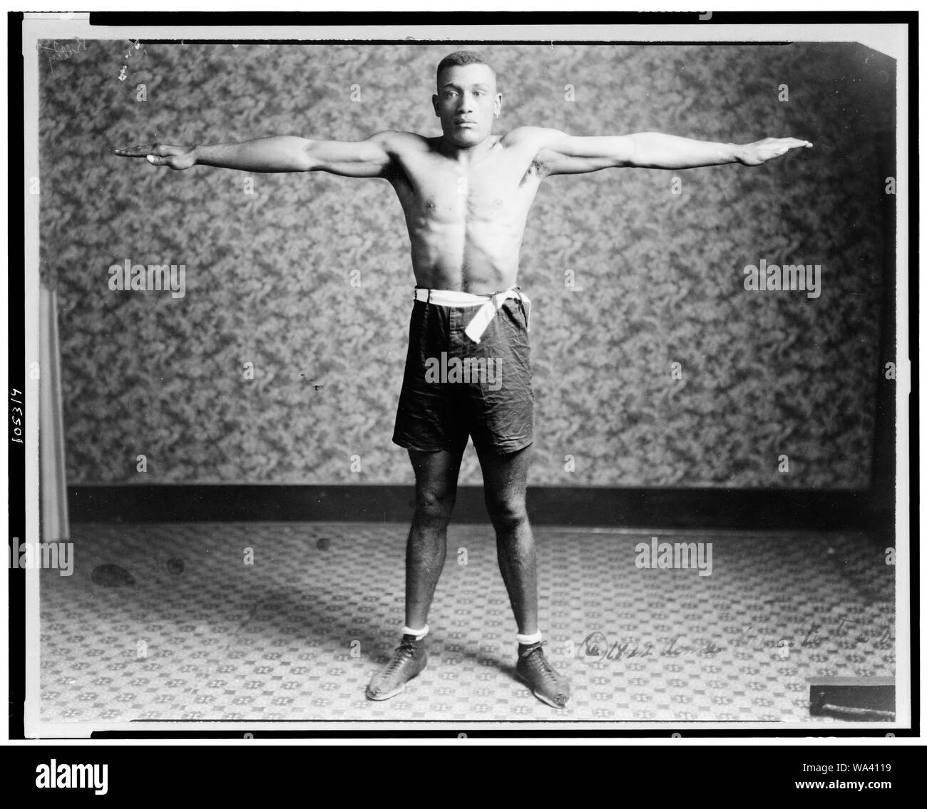 Boxer Tut Jackson vestita in tronchi di inscatolamento di intera lunghezza verticale, in piedi, rivolto verso la parte anteriore, con le braccia allungate fuori dai suoi lati, mostrando la sua raggiungere Foto Stock