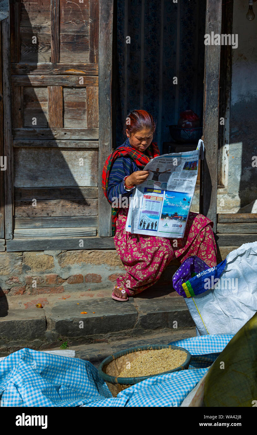 Le donne nepalesi in abiti tradizionali è la lettura di un quotidiano in una porta d'ingresso in una giornata di sole Foto Stock