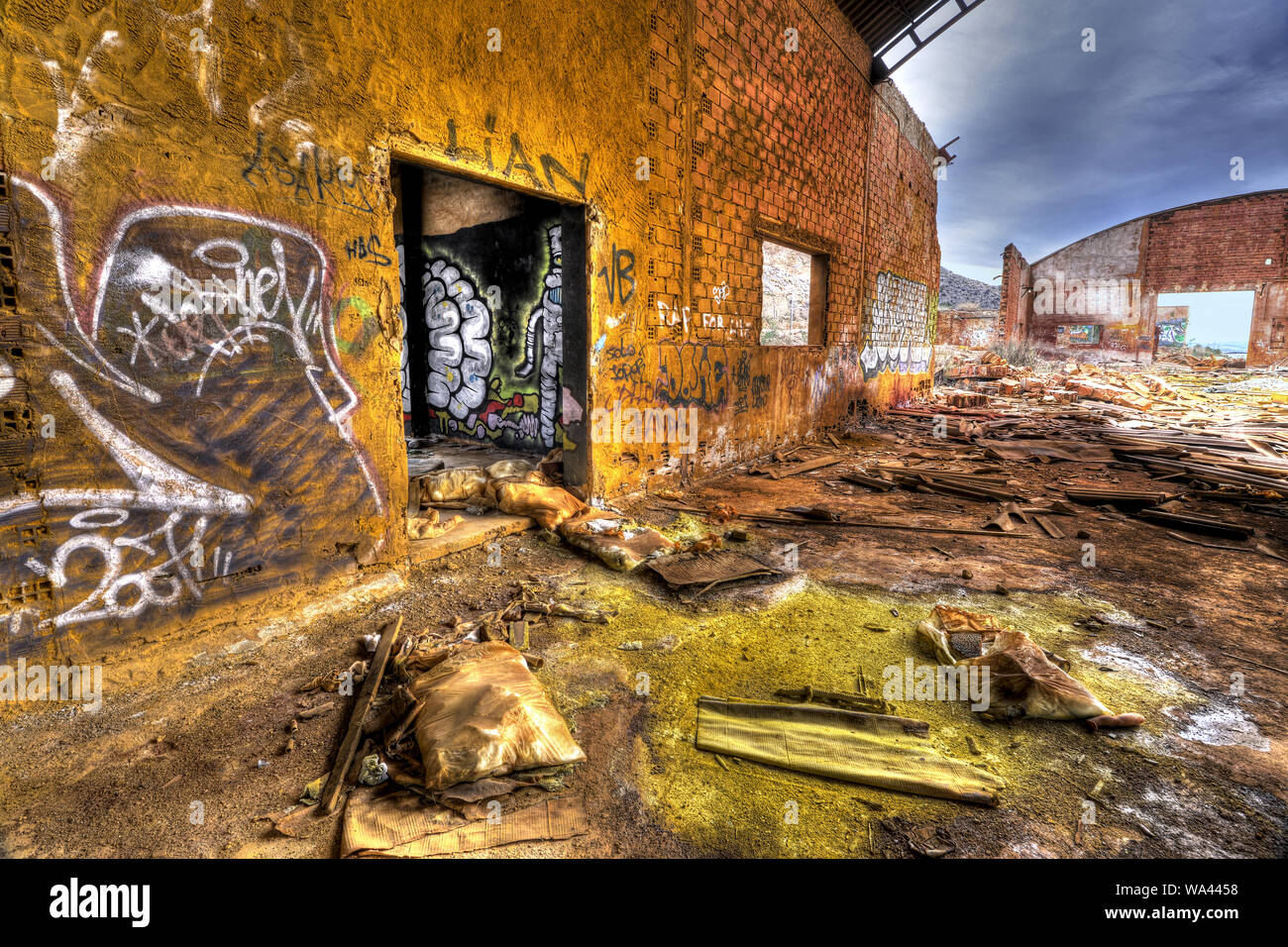 Vecchia fabbrica abbandonata pianta con sostanze chimiche a terra e grafitti a muri di mattoni Foto Stock