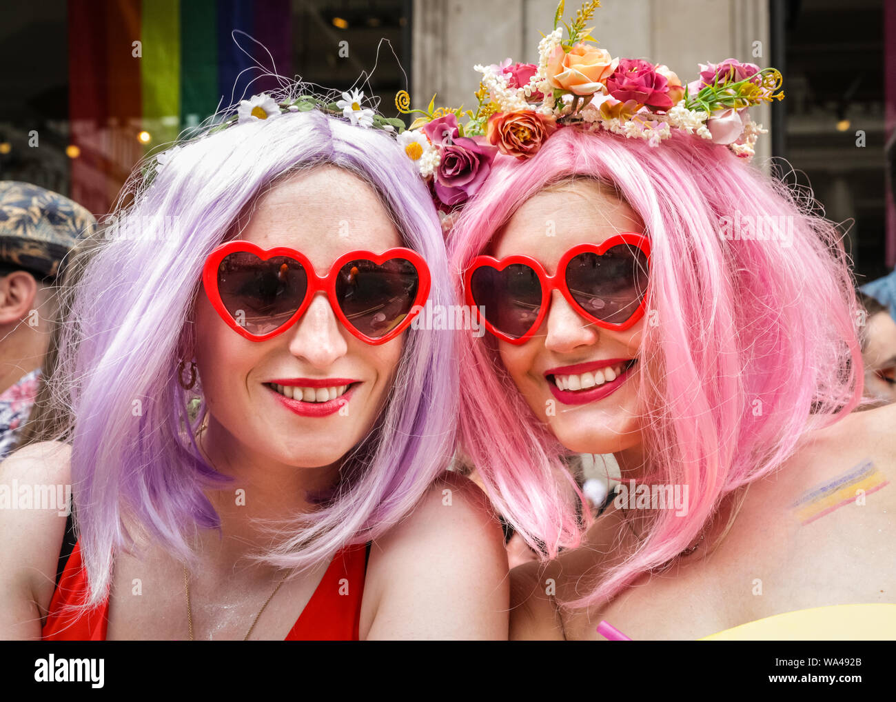 Due donne gli spettatori in un colorato oink parrucche e abiti al Pride a Londra Parade, London, Regno Unito Foto Stock