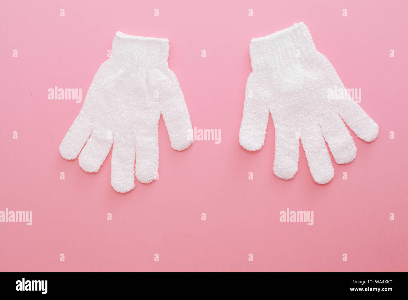 Donna massaggio esfoliante con guanto per doccia su sfondo rosa.i guanti per uso nella doccia per massaggio e scrub. La bellezza dello sfondo con cosmetic prod Foto Stock