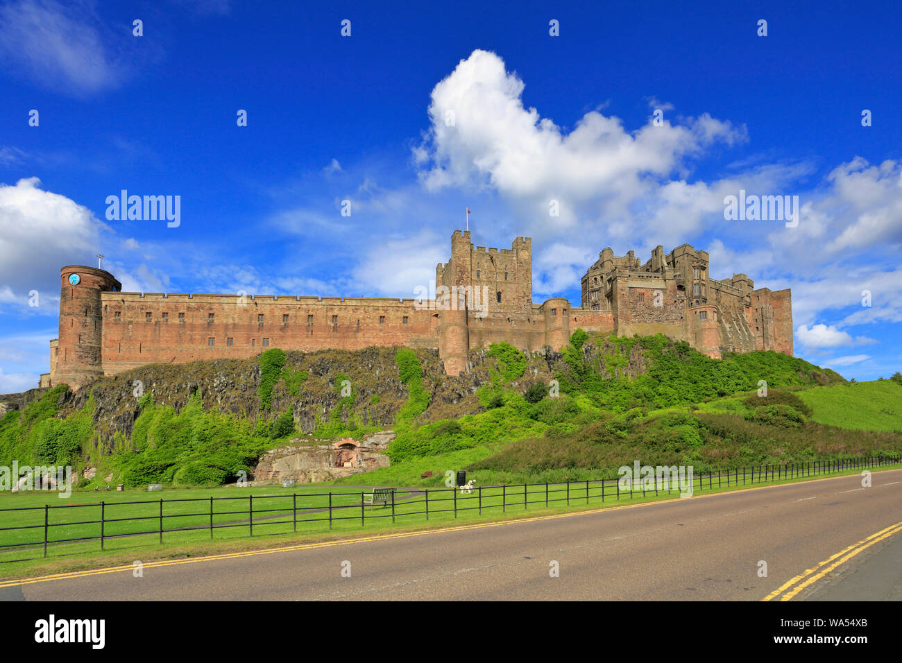 Il castello di Bamburgh dalla strada del Northumberland sentiero costiero, Bamburgh, Northumberland, Inghilterra, Regno Unito. Foto Stock