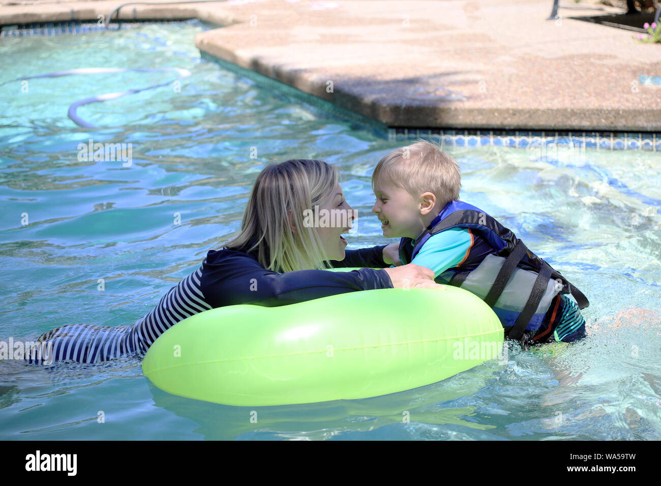 Madre e figlio godendo un momento giocoso in piscina. Foto Stock